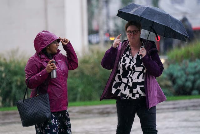 <p>People walk by Centenary Square in Birmingham during a rainy morning as Met Office issues fresh weather warning </p>